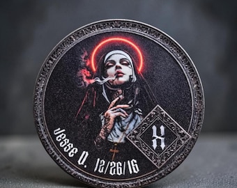 Könnte beinhalten: Eine kreisförmige Metallmünze mit einer Nonne mit leuchtend rotem Heiligenschein, die eine Zigarette raucht. Das Design enthält den Text 'Jesse V. 12/26/16' und ein rautenförmiges Emblem mit dem Buchstaben 'H' auf schwarzem Hintergrund.