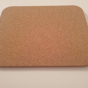 May include: A brown cork coaster with a slightly rounded rectangular shape.