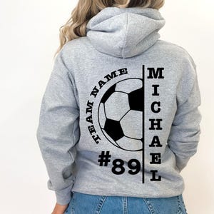 May include: Gray hooded sweatshirt with a black soccer ball graphic and the text "TEAM NAME #89 MICHAEL" printed on the back.