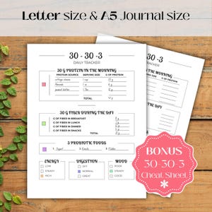 Op de afbeelding: Een witte dagelijkse tracker journal met de tekst "30-30-3" en "Letter size & A5 Journal size". Het journal bevat secties voor eiwitten, vezels en probiotische voedingsmiddelen, met een bonus cheat sheet. Het journal ligt op een houten oppervlak.