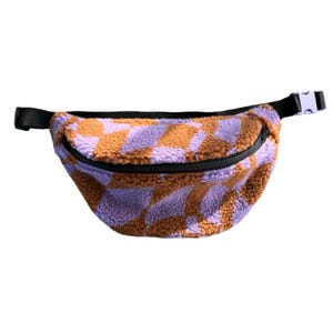 Könnte beinhalten: Eine braune und violette karierte Bauchtasche mit einem schwarzen Reißverschluss und einem schwarzen Gurt.