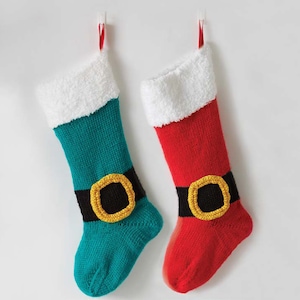 May include: Two knitted Christmas stockings with white fur trim, one red and one teal, with black and gold belts.