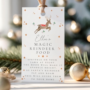 Può includere: Un'etichetta regalo rettangolare bianca con un'illustrazione di renna marrone, stelle arancioni e accenti di agrifoglio verde. Il testo recita: Ellie's MAGIC REINDEER FOOD. SPRINKLE ON YOUR LAWN AT NIGHT. THE MOON WILL MAKE IT SPARKLE BRIGHT. AS SANTA'S REINDEER FLY AND ROAM THIS WILL GUIDE THEM TO YOUR HOME.