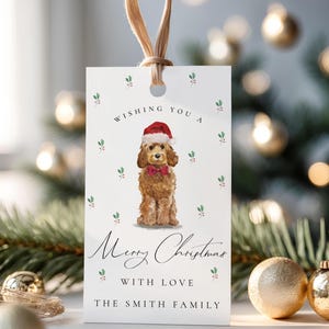 May include: A white Christmas gift tag with a watercolor illustration of a dog wearing a Santa hat and bow tie. The tag reads "Wishing You a Merry Christmas With Love The Smith Family."