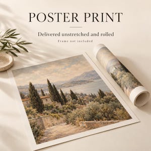 The image is a poster print featuring a landscape scene with trees, buildings, and a body of water. The print is rolled up and placed on a surface, along with a plant and a small bowl.