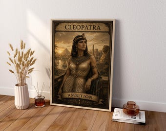 May include: A rectangular framed wall art print featuring a portrait of Cleopatra in a golden dress, with the text CLEOPATRA at the top and AMBITION at the bottom. The background depicts an ancient Egyptian landscape with pyramids and a sphinx.
