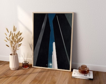 May include: A framed vertical art print featuring a low-angle view of dark, towering skyscrapers against a deep blue night sky with a small moon. The composition emphasizes sharp geometric shadows and vertical lines, creating a stark contrast between the dark buildings and the illuminated sky.