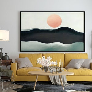 May include: A yellow sofa with two pillows and a throw blanket sits in front of a large abstract painting of a pink sun setting over a dark blue and green landscape. A coffee table with a vase of white flowers sits in front of the sofa.