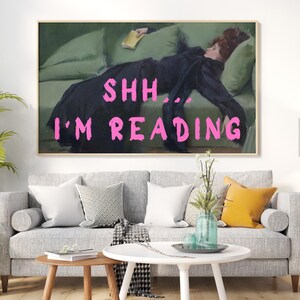 Op de afbeelding: Een schilderij van een vrouw die op een bank ligt en een boek leest. De tekst "Shh... I'm reading" staat in roze letters op het schilderij.