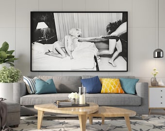 May include: A black and white framed wall art print depicting a person kneeling on a bed pulling the waistband of another person's underwear. The scene is set in a bedroom with a lamp and curtains visible in the background of the photograph.