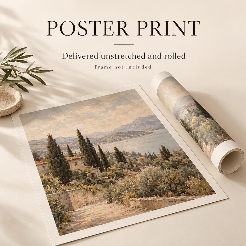 The image is a poster print featuring a landscape scene with trees, buildings, and a body of water. The print is rolled up and placed on a surface, along with a plant and a small bowl.