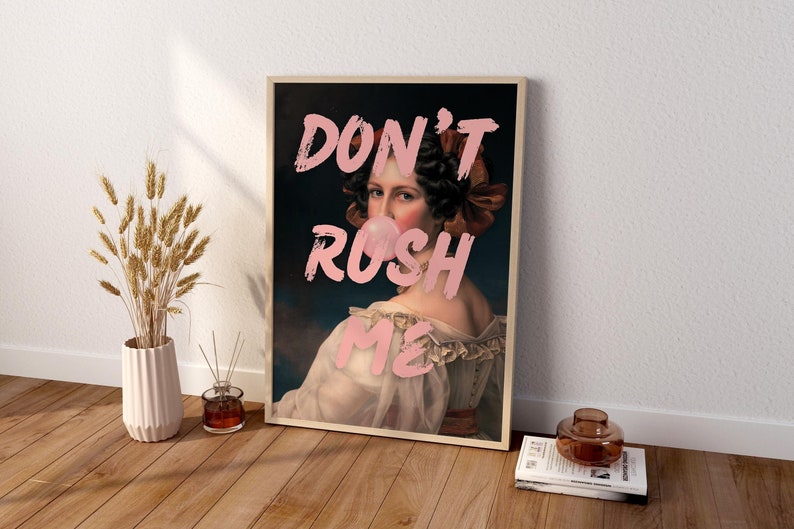 K&ouml;nnte beinhalten: Ein gerahmter Druck einer Frau mit einer rosa Blase im Mund. Der Text "DON'T RUSH ME" ist in rosa Buchstaben &uuml;ber dem Bild geschrieben.