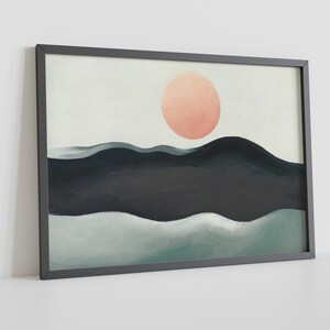May include: A framed abstract painting with a peach-colored circle in the center, above a dark blue and green landscape. The painting is framed in a black frame.