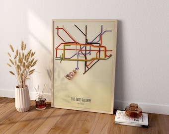 May include: A framed vertical poster featuring a stylized map of London Underground lines in various colors on a cream background. The text reads THE TATE GALLERY by Tube. A paint tube is attached to the bottom of the map, with a line of paint extending from it to form part of the transit network.