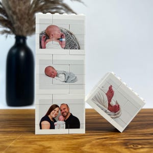 Peut inclure: Un bloc photo en briques blanches avec trois images d'un nouveau-n&eacute; et un portrait de famille. Le bloc est fait de briques imbriqu&eacute;es, avec un quatri&egrave;me bloc affichant les pieds d'un b&eacute;b&eacute;. Les images sont imprim&eacute;es sur les briques.