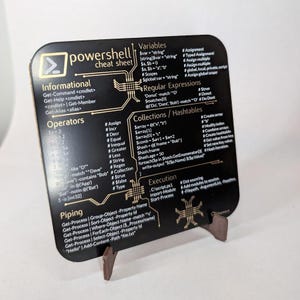 Peut inclure: Une feuille de triche noire avec des lettres dorées pour les commandes PowerShell. La feuille de triche est divisée en sections pour les variables, les expressions régulières, les collections et les tables de hachage, les opérateurs, l'exécution et la canalisation. La feuille de triche comprend des exemples de commandes et de syntaxe PowerShell.