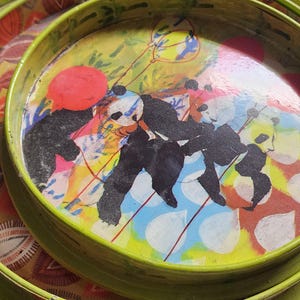 Puede incluir: Tres bandejas de anidación verde y amarillo con un diseño colorido que presenta pandas, globos y flores. Las bandejas están hechas de un material ligero y son perfectas para servir refrigerios o bebidas.