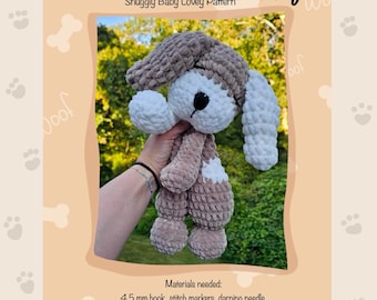Puede incluir: Un muñeco de apego de cachorro tejido a mano en tonos marrón, blanco y beige. El cachorro tiene un gorro, orejas largas y un aspecto suave y texturizado. El texto "Sweet Dreams Puppy" y "Snuggly Baby Lovey Pattern" son visibles.