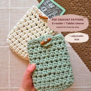 May include: Two crochet e-reader/tablet sleeves in cream and mint green. Each sleeve has a wooden toggle closure. The text on the image reads: PDF CROCHET PATTERN: E-reader / Tablet sleeve explained step-by-step + adjustable size.