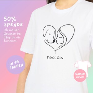 Könnte beinhalten: Weißes T-Shirt mit einer schwarzen Strichzeichnung eines Hundes und eines menschlichen Gesichts in Herzform. Das Wort "rescue" ist darunter gedruckt. Zusätzlicher Text enthält "50% SPENDE" und "IN 16 FARBEN".