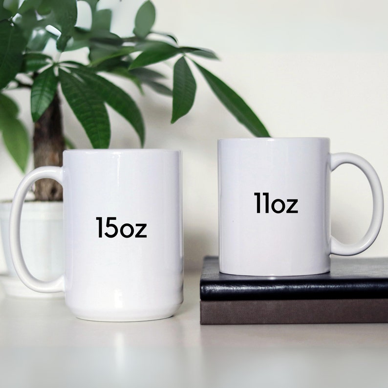 May include: Two white ceramic mugs with black text. The mug on the left says "15oz" and the mug on the right says "11oz".