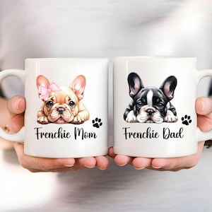 Left mug shows a Fawn French Bulldog with a pink bow while on the right mug shows a black and white French Bulldog without a bow. Left mug says Frenchie Mom and Right mug says Frenchie Dad with a paw print.