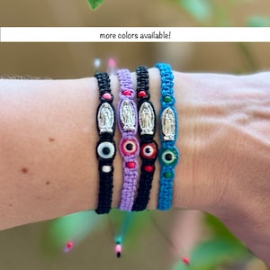 May include: A collection of handmade bracelets in various colors, including black, purple, and blue. Each bracelet features a central religious charm and is accented with colorful beads. The text "more colors available!" is displayed.