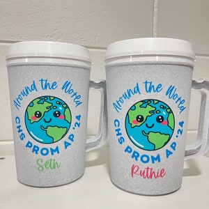 May include: Two gray insulated cups with white lids and handles. Each cup features a cartoon earth with a smiling face and the text "Around the World" in blue. The text "CHS PROM AP '24" is printed below the earth. One cup has the name "Seth" printed below the date, and the other cup has the name "Ruthie" printed below the date.