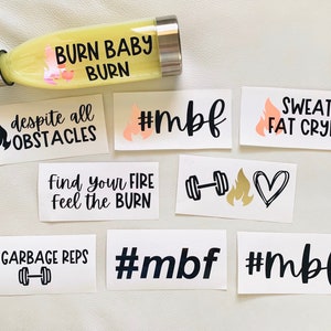 May include: A set of motivational fitness stickers with phrases like "Burn Baby Burn", "Sweat=Fat Crying", and "Find Your Fire Feel the Burn". The stickers are printed in black on white backgrounds and feature a variety of designs, including flames, hearts, and dumbbells.