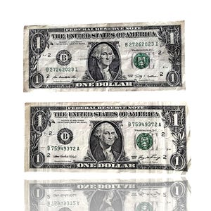 Può includere: Sono mostrate due banconote da un dollaro statunitense, con un ritratto di George Washington. Le banconote sono leggermente usurate, con la scritta "ONE DOLLAR" ben visibile. Le banconote sono su sfondo bianco.