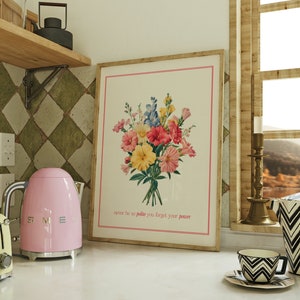 Może przedstawiać: Wydruk w ramie z bukietem kolorowych kwiatów w odcieniach różowego, żółtego, niebieskiego i czerwonego. Wydruk zawiera tekst "never be so polite you forget your power" na dole.