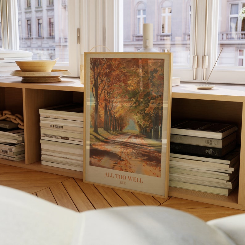 May include: A framed print of a painting depicting a path lined with trees in autumn colors. The print has the text "ALL TOO WELL" and "RED" below the image.