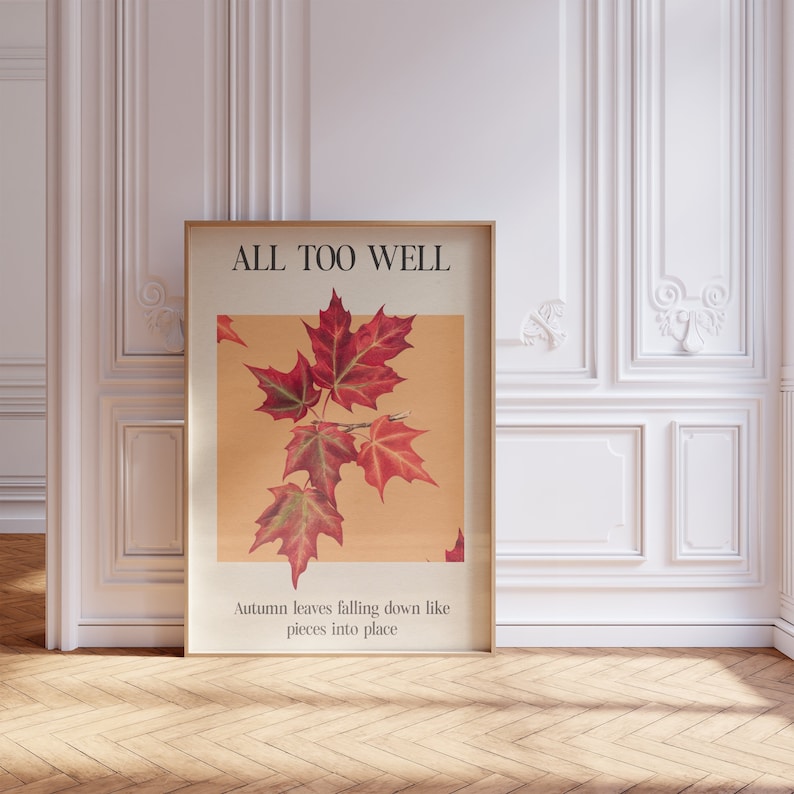 May include: A framed poster with the text "ALL TOO WELL" and a picture of red maple leaves. The text below the image reads "Autumn leaves falling down like pieces into place."