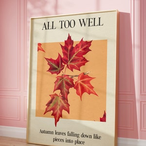 May include: A framed print with the text "ALL TOO WELL" and a picture of red maple leaves on a light orange background. The text below the image reads "Autumn leaves falling down like pieces into place."