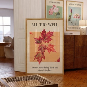 May include: A framed print with the text "ALL TOO WELL" and a quote about autumn leaves falling down like pieces into place. The print features a vintage illustration of red maple leaves on a peach background.