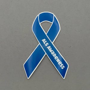 May include: A blue ribbon with white trim, featuring the text "ALS Awareness" in white. The ribbon is a symbol of support and awareness for Amyotrophic Lateral Sclerosis, also known as Lou Gehrig's disease. The ribbon is set against a gray background.