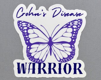 Pode incluir: Um autocolante branco com um gráfico de borboleta roxa no centro. O texto "Crohn's Disease" está impresso em letra cursiva roxa acima da borboleta, e a palavra "WARRIOR" está escrita em letras maiúsculas azul-escuras abaixo.