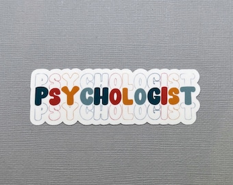 May include: A white sticker with the word "PSYCHOLOGIST" in a retro font. The text is in a layered design with colors of orange, red, blue, and teal. The sticker is on a gray textured surface.