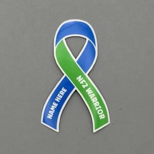 May include: A blue and green awareness ribbon sticker with the text "NF2 WARRIOR" and "NAME HERE". The ribbon is a symbol of support and solidarity.
