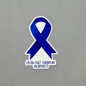 May include: Blue awareness ribbon sticker with the text "Cri du Chat Syndrome awareness".