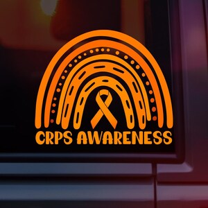 May include: Orange and black sticker featuring a stylized rainbow design with a ribbon in the center. The text "CRPS AWARENESS" is displayed in orange below the rainbow. The sticker is likely for raising awareness.