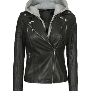 May include: Black leather jacket with a grey hooded insert. The jacket features a diagonal zip closure, multiple zipped pockets, and quilted shoulder detailing. A stylish outerwear piece.