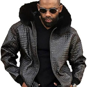 Könnte beinhalten: Eine schwarze Lederjacke mit Kroko-Prägung. Die Jacke hat einen Reißverschluss, eine Kapuze mit Pelzbesatz und einen gerippten Strickkragen, Bündchen und Bund.