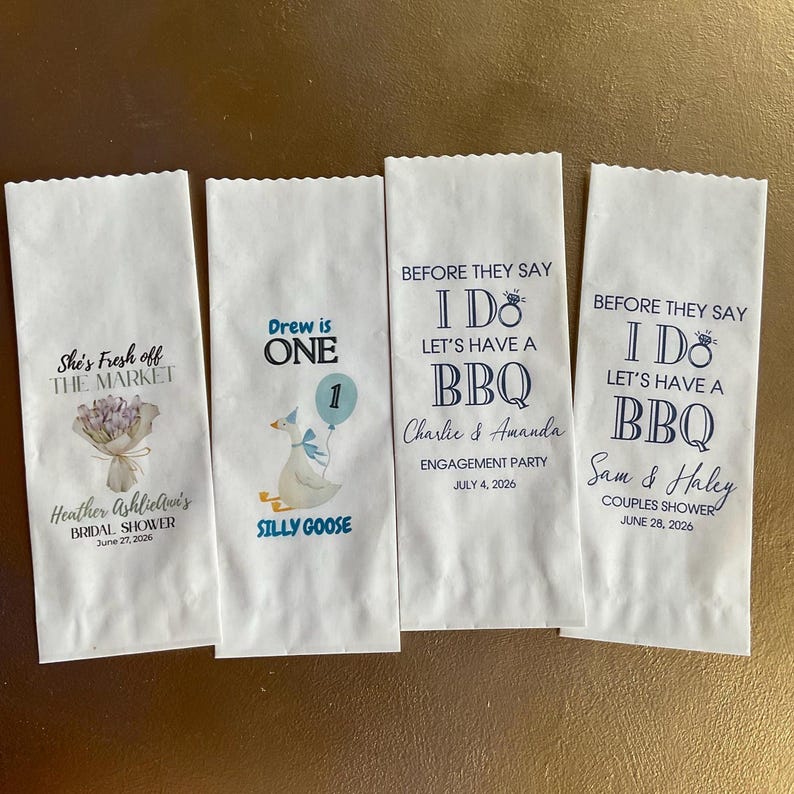 Op de afbeelding: Vier witte papieren zakjes met geschulpte bovenranden. Het eerste zakje heeft een bloemenboeket en de tekst She's Fresh off THE MARKET Heather AshlieAnn's BRIDAL SHOWER June 27, 2026. Het tweede toont een gans en ballon met de tekst Drew is ONE SILLY GOOSE. Het derde en vierde zakje tonen BEFORE THEY SAY I DO LET'S HAVE A BBQ met de namen Charlie & Amanda of Sam & Haley, evenementtypes en datums.