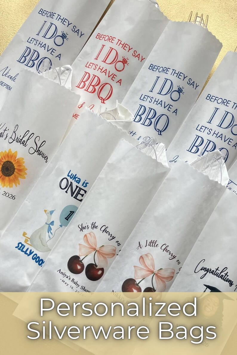 Op de afbeelding: Een verzameling witte papieren bestekzakjes met diverse bedrukte ontwerpen, waaronder teksten zoals Before They Say I Do Let's Have A BBQ, Luka is One en She's the Cherry on Top, naast afbeeldingen van zonnebloemen, ganzen en kersen.