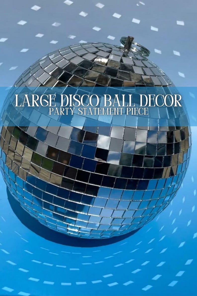 Op de afbeelding: Een bolvormige discobal bedekt met kleine, reflecterende zilveren spiegeltegels. Aan de bovenkant is een metalen ring bevestigd om op te hangen. De tekst "LARGE DISCO BALL DECOR PARTY STATEMENT PIECE" staat over het oppervlak heen.
