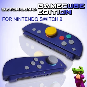 May include: Two blue Nintendo Switch controllers with a GameCube design. The controllers have a yellow joystick, grey, red, and teal buttons. The text "Gator-Con 2" and "GameCube Edition" are visible.