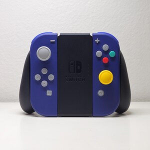 May include: A blue and black Nintendo Switch controller with a circular yellow button and a gray joystick. The controller has the text "Nintendo Switch" printed on the front.