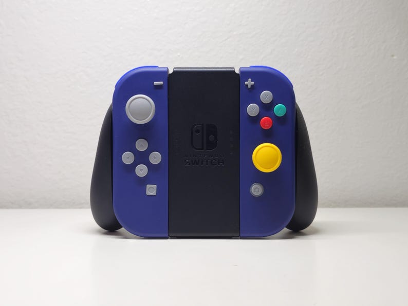 May include: A blue and black Nintendo Switch controller with a circular yellow button and a gray joystick. The controller has the text "Nintendo Switch" printed on the front.