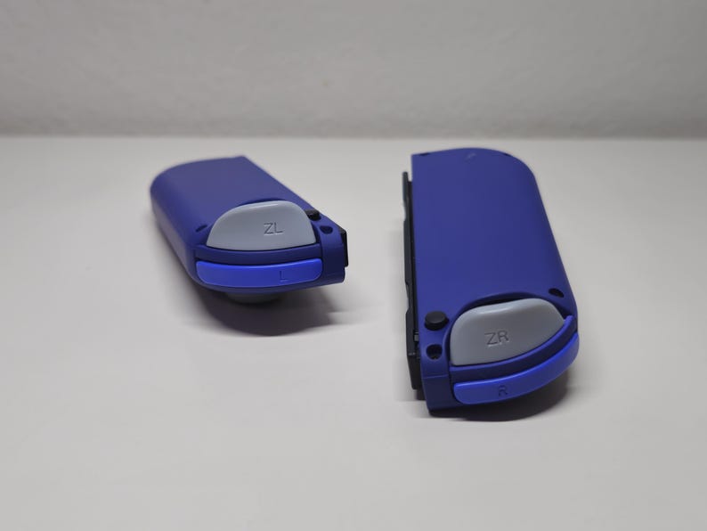 May include: Two blue Nintendo Switch Joy-Con controllers with gray buttons labeled "ZL" and "ZR".